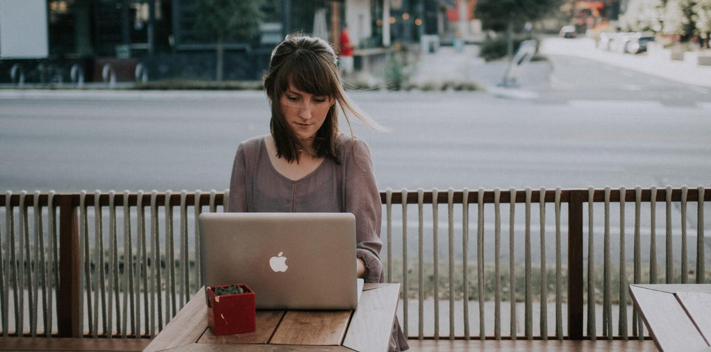 woman sitting on a bench and working on laptop