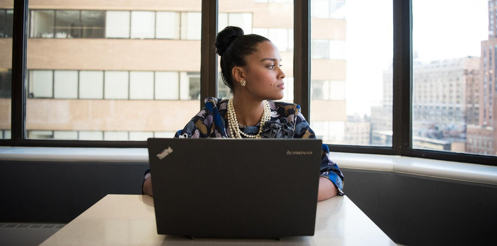 A woman sits in front of the computer and looks in the window 