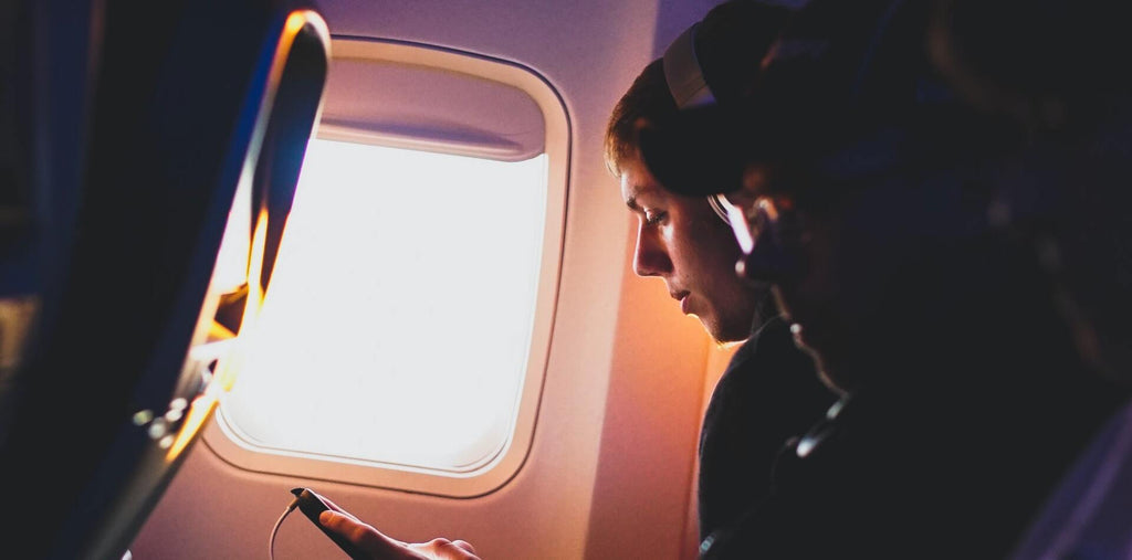 A man in the plane looking on his smartphone