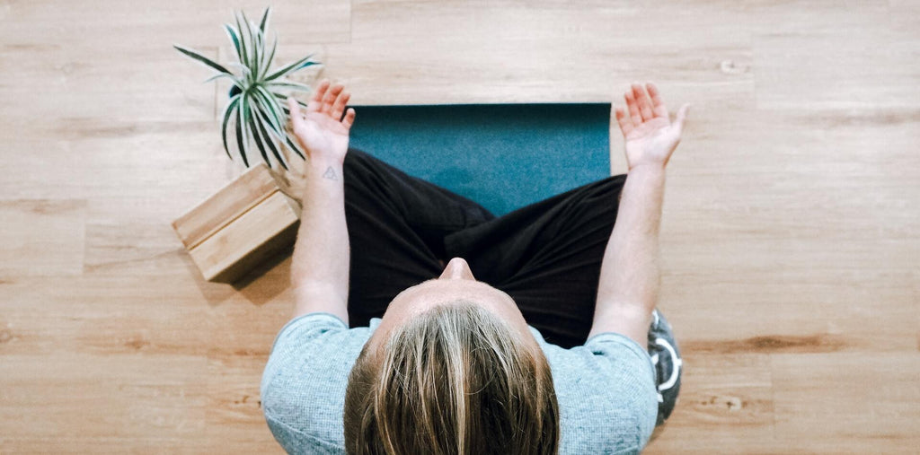 Man meditating at home on a yoga mat