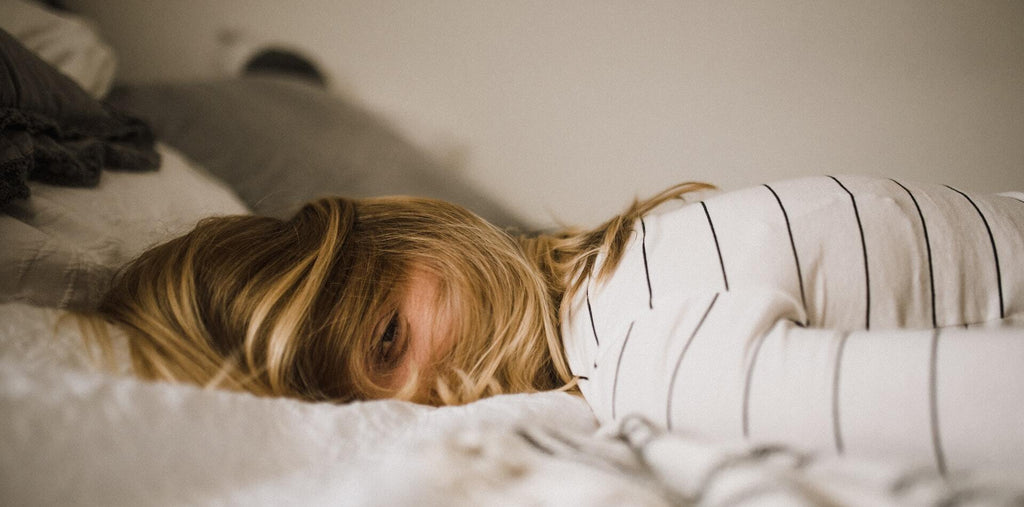 Woman lays on a white bed