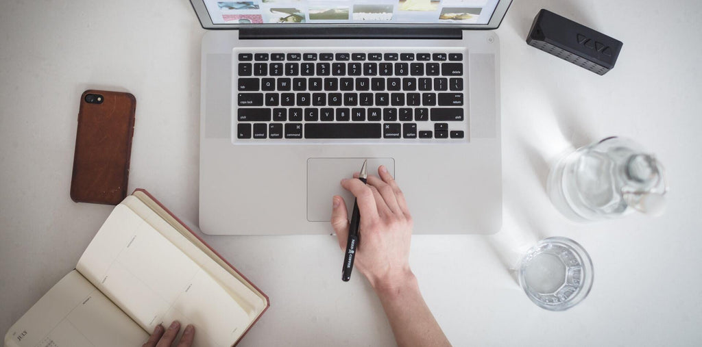 Working person with the laptop and a bottle of water stays hydrated during work