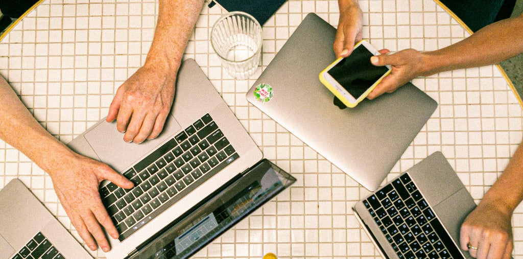 People working at one desk with their laptops