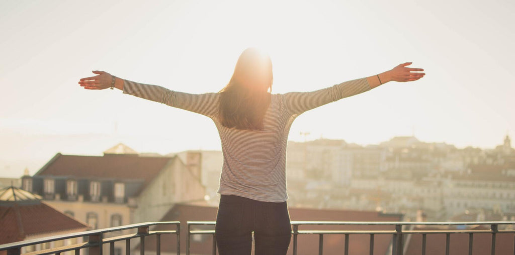 woman stands in front of sunshine