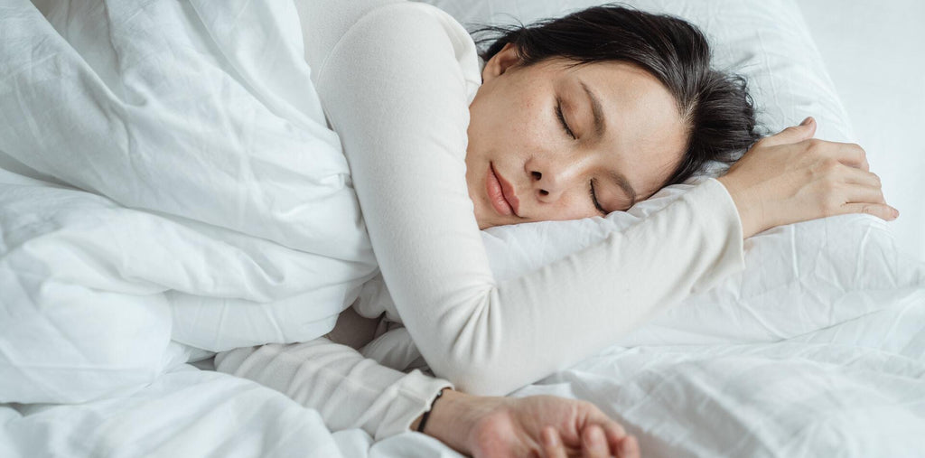 A woman calmly sleeping on white sheets