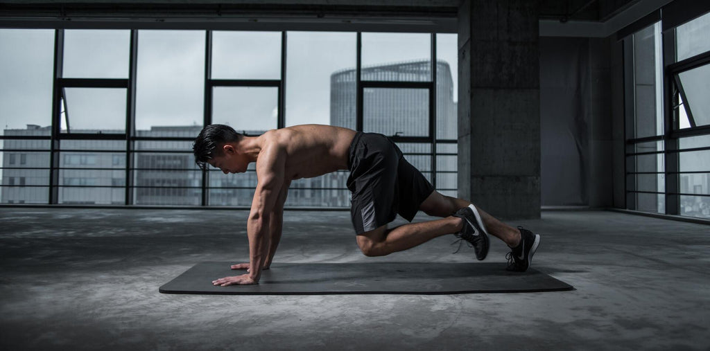 A man standing in a plank while being in a gym