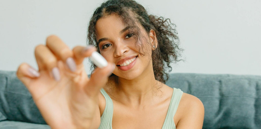 smiling woman holds a supplement in her hand