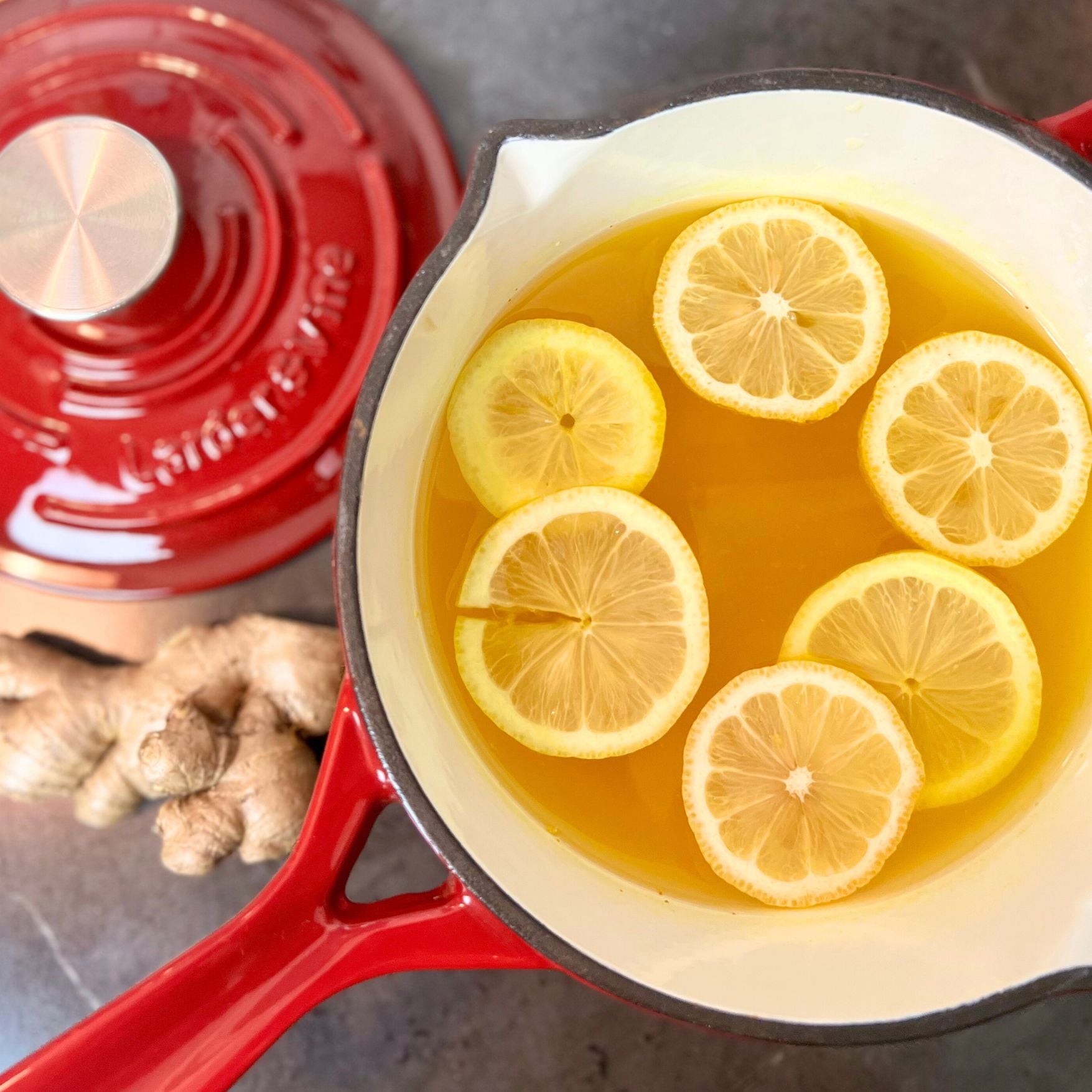 Lemon Ginger Turmeric Tea in front of Cabernet red Saucepan
