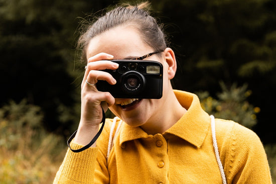 Persona que sostiene una cámara de apuntar y disparar de película de 35 mm.