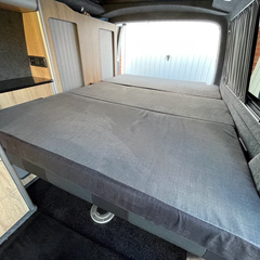 A set of three cushions for a camper van that make up to a full bed. They are thick foam, about 10cm and are dark grey on the sides and underside and lighter grey on the top. The top of the foam has a memory foam layer to make it extra comfy. One of the cushions has a cut out so it fits round the shaping of the inside of the van.