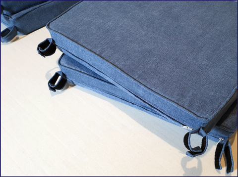 A set of custom size and shape wooden chair cushions made up in mid blue hardwearing upholstery fabric. Each seat cushion has two sets of velcro tabs to keep the cushions securely attached to the chair.