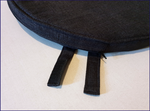 A bespoke shaped chair cushion in a charcoal dark grey hardwearing fabric with a pair of velcro tabs at the back to wrap around the spindles of the chair to keep it in place.