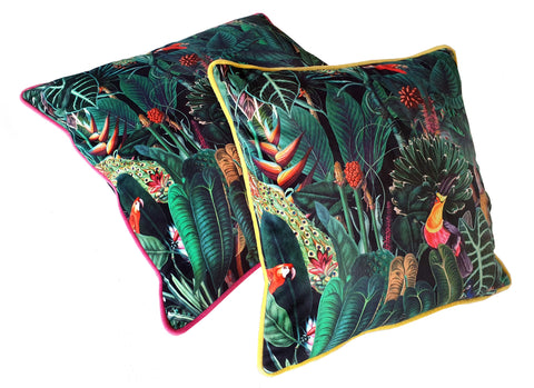 A pair of throw scatter cushions in a vivid jungle design velvet fabric. Both covers have zips and one is piped in yellow velvet and the other is piped in pink velvet.