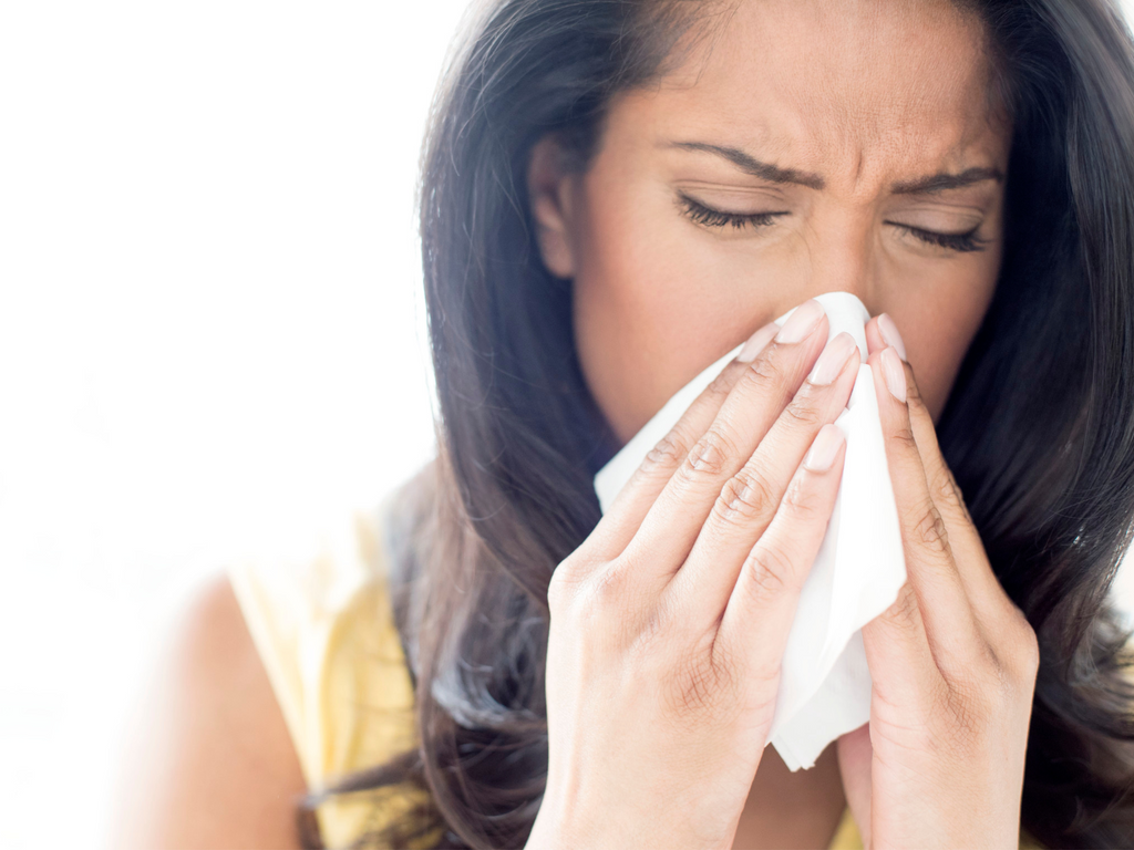 Woman sneezing in a tissue