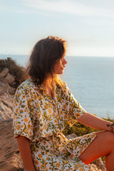 Frau in Blumenhemdkleid schaut auf das Meer