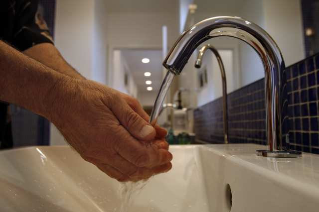 hands being washed under a sink's faucet