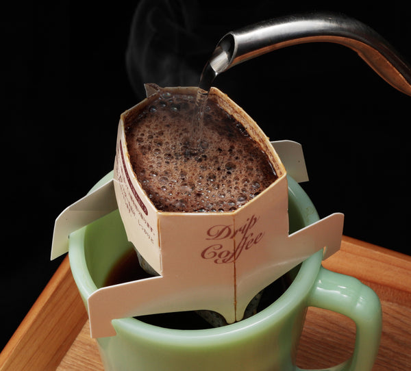 Pouring hot water into a drip coffee bag over a mug.