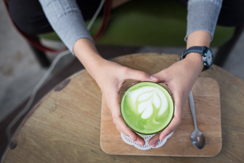 person holding a matcha latte at a cafe