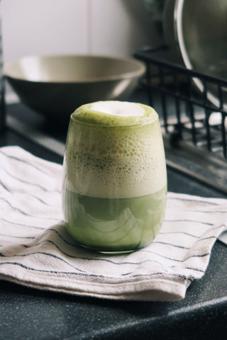 frothy matcha latte sitting on table 