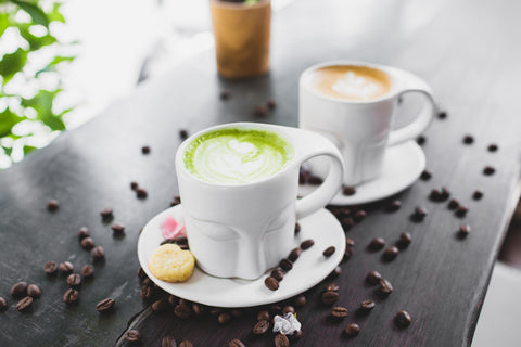 matcha and coffee in white coffee cups on a black cafe table