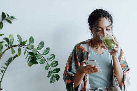 woman drinnking matcha for pcos while on phone