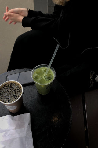 person sitting beside two cups of matcha and coffee