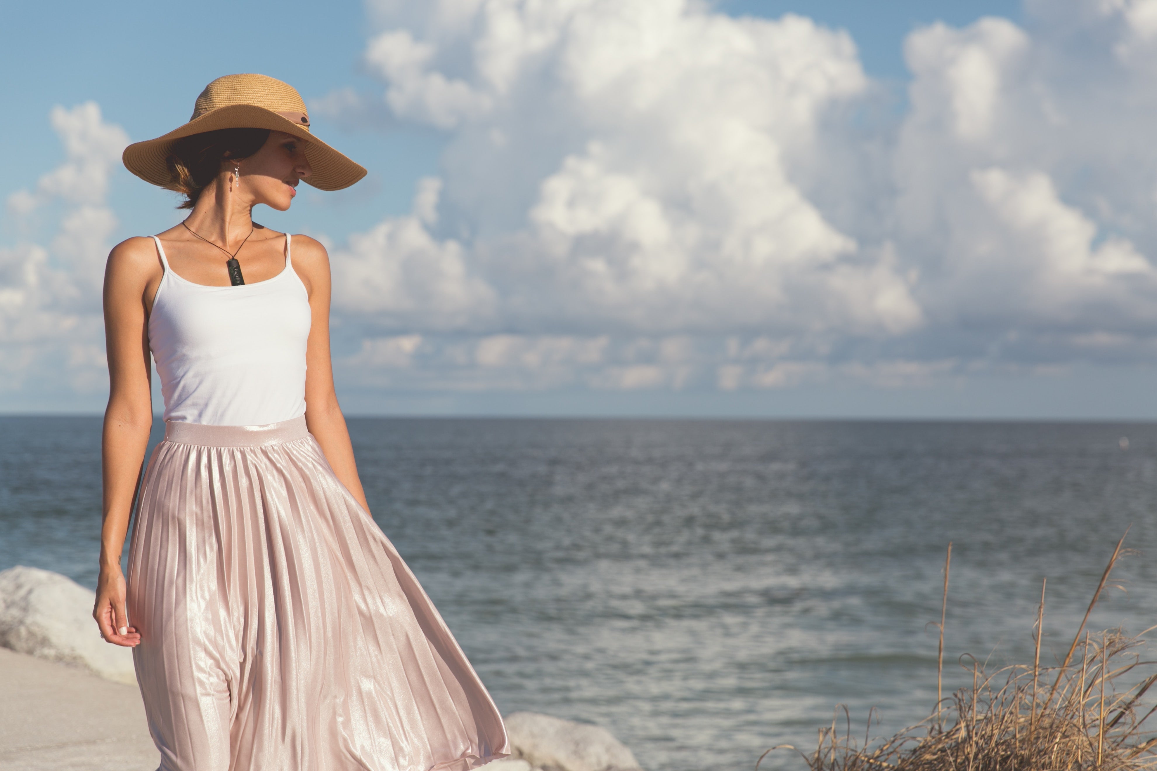 woman wearing a classic skirt and hat by the ocean