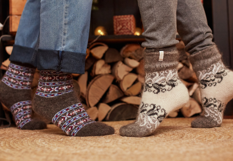 Man's and woman's legs standing opposite of each other wearing wool socks and jeans.