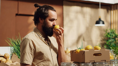 Homme sentant un citron mûr.