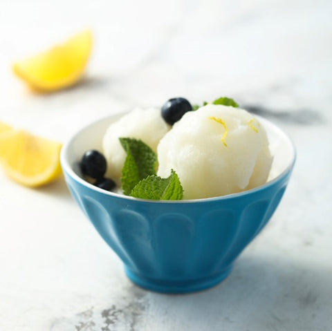 Un bol bleu rempli de sorbet au limoncello, garni de myrtilles et de menthe fraîche.