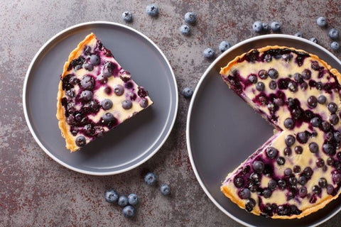 Une tarte au limoncello et aux myrtilles dans deux moules à tarte avec une part découpée.