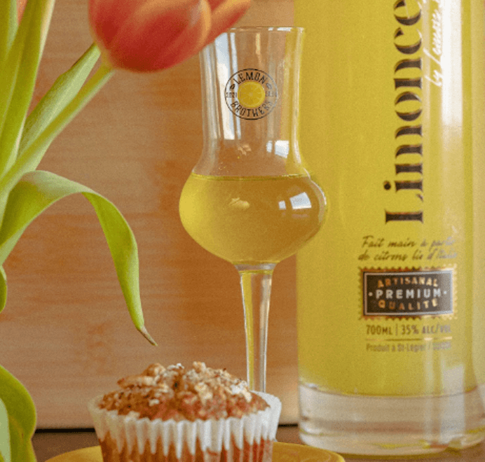 Limonceflo in a Lemon Brothers branded glass and full bottle behind a bran muffin and a bunch of tulips.