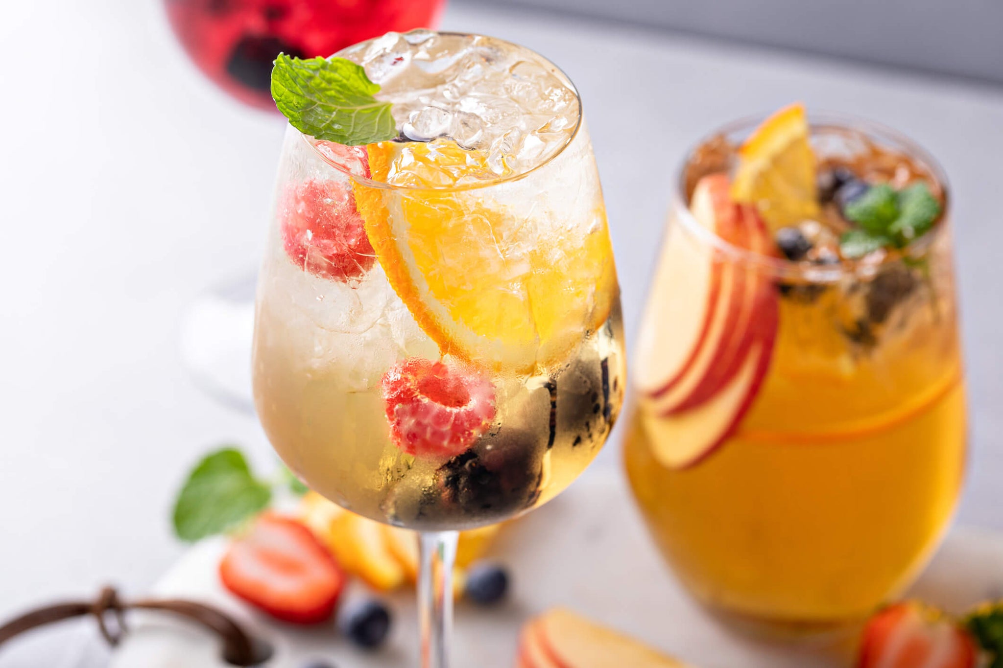 Two Limoncello Spritzers with a mixture of fruit and mint garnishes.