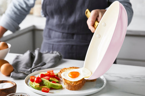 A fried egg sliding out of a GreenPan Reserve Blush 10" Frypan and onto a piece of toast.