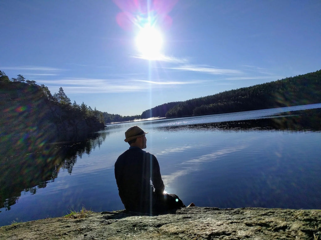 Witali sitting by a lake from behind, in the midst of untouched nature.