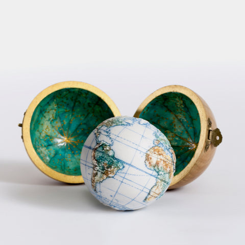 a miniature globe sitting outside a spherical wooden case 