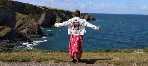 artist Siobhan Purdy wearing a jacket with painted back overlooking the coastline at Port Isaac in Cornwall 