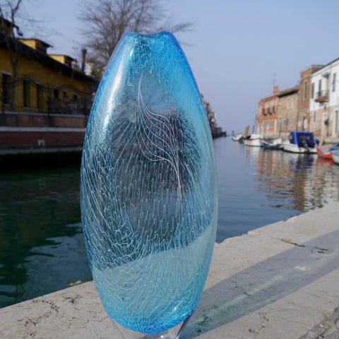 Blue glass vase photographed next to canal in Venice 