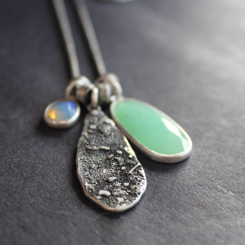 three part silver necklace with a large green stone and a small purple one