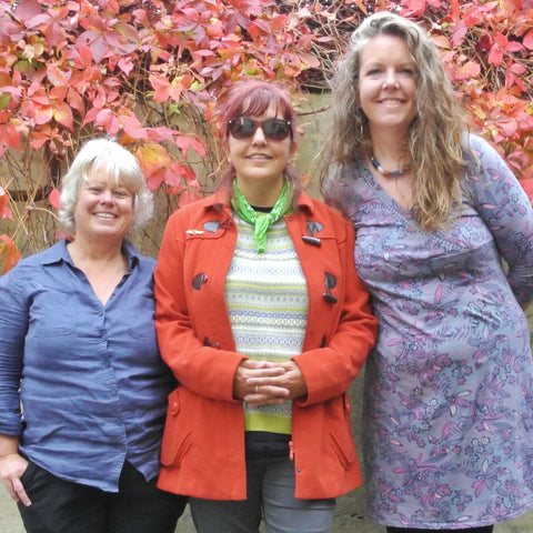 three women: poets Ali Tangye and Rene Crouch with artist Siobhan Purdy standing in front of a red leafed bush