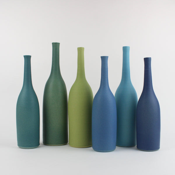a row of Lucy Burley ceramic bottles in shades of blues and greens 