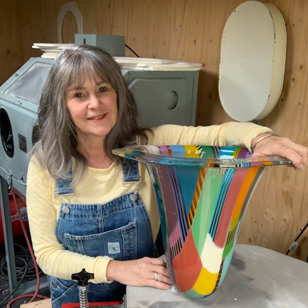 Glass artist Ruth Shelley in her studio with large coloured glass vessel