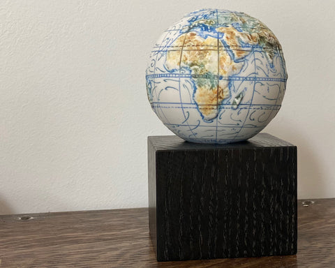 miniature globe on a dark wooden stand it was made by loraine Rutt of the Little Globe company 