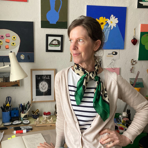 artist Sophie Harding in her studio in front of a selection of her colourful still life paintings