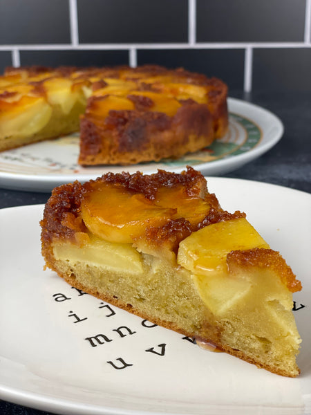 Slice of Caramelized Apple Olive Oil Cake in foreground with cake on platter in the background