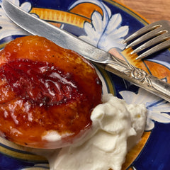 Grilled peach half with whipped cream on a Deruta style ceramic plate