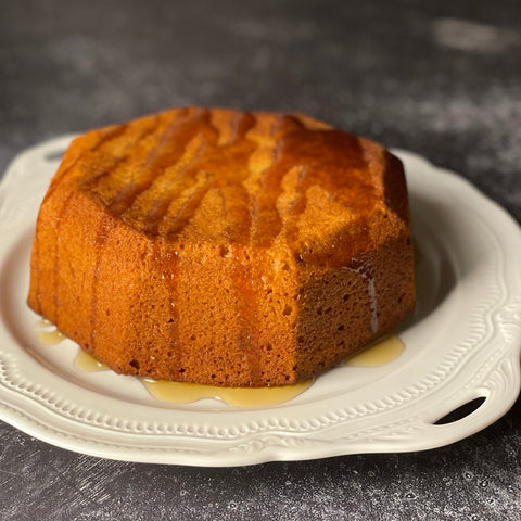 Olive oil honey cake, drizzled with honey and rosemary syrup, on a delicate Limoges plate.