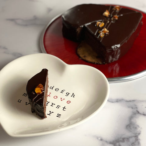 Slice of chocolate almond olive oil torte is shown on a heart shaped dessert plate.