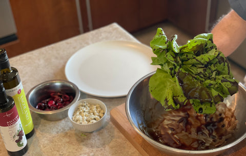 Donald dips an entire head of butter lettuce into a large bowl coated with vinaigrette