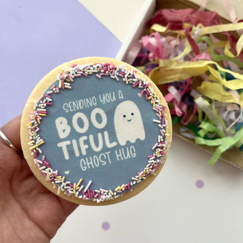 A round shortbread iced cookie for Halloween with "Sending you a bootiful ghost hug"